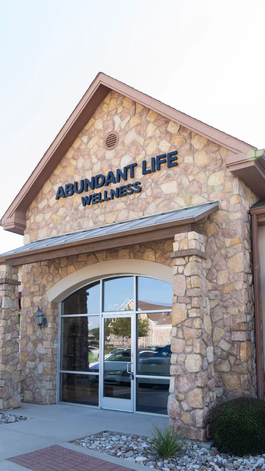The entrance to Abundant Life Wellness Center — a stone building with the practice name above the door and Suite 700 on the glass