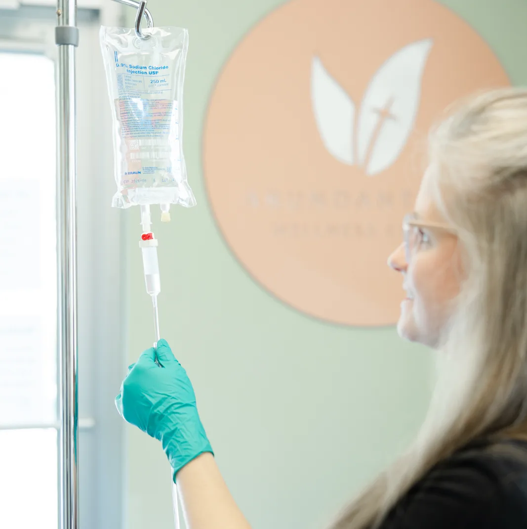 A team member adjusting a hanging IV drip line by the practice mark