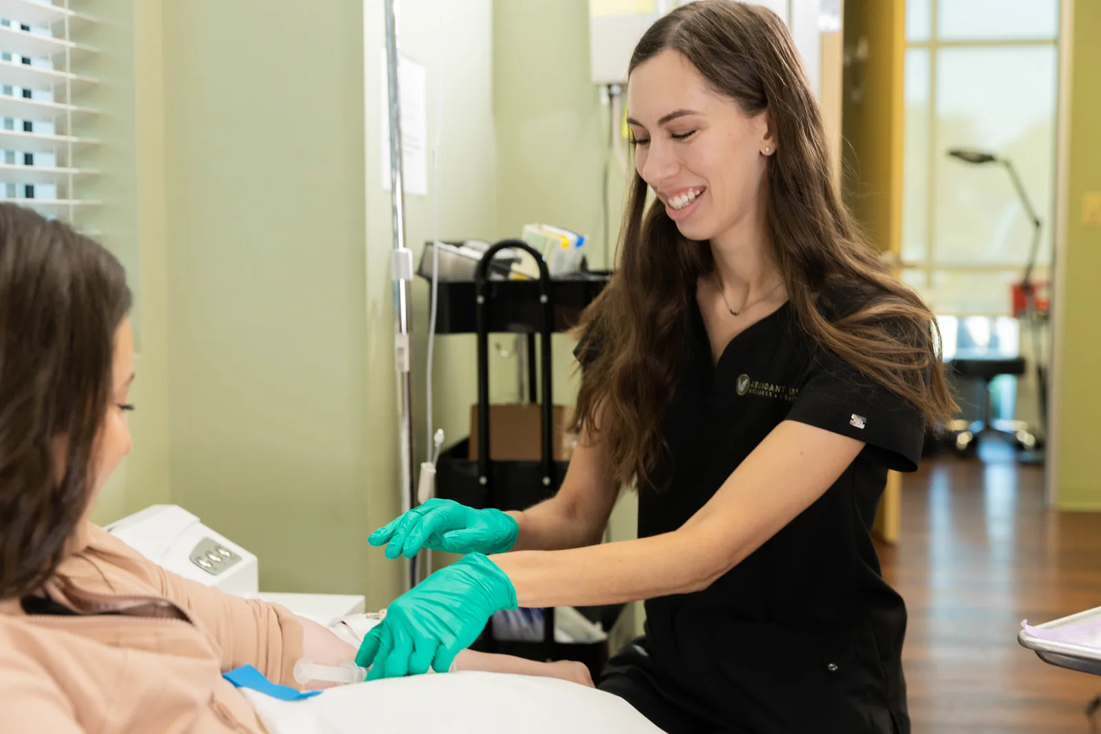 A team member tending a seated client's IV line during an infusion