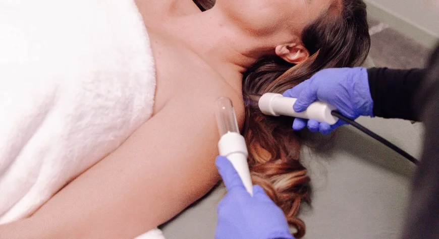 A LymphStar session — two glass applicators worked along the client's neck and shoulder