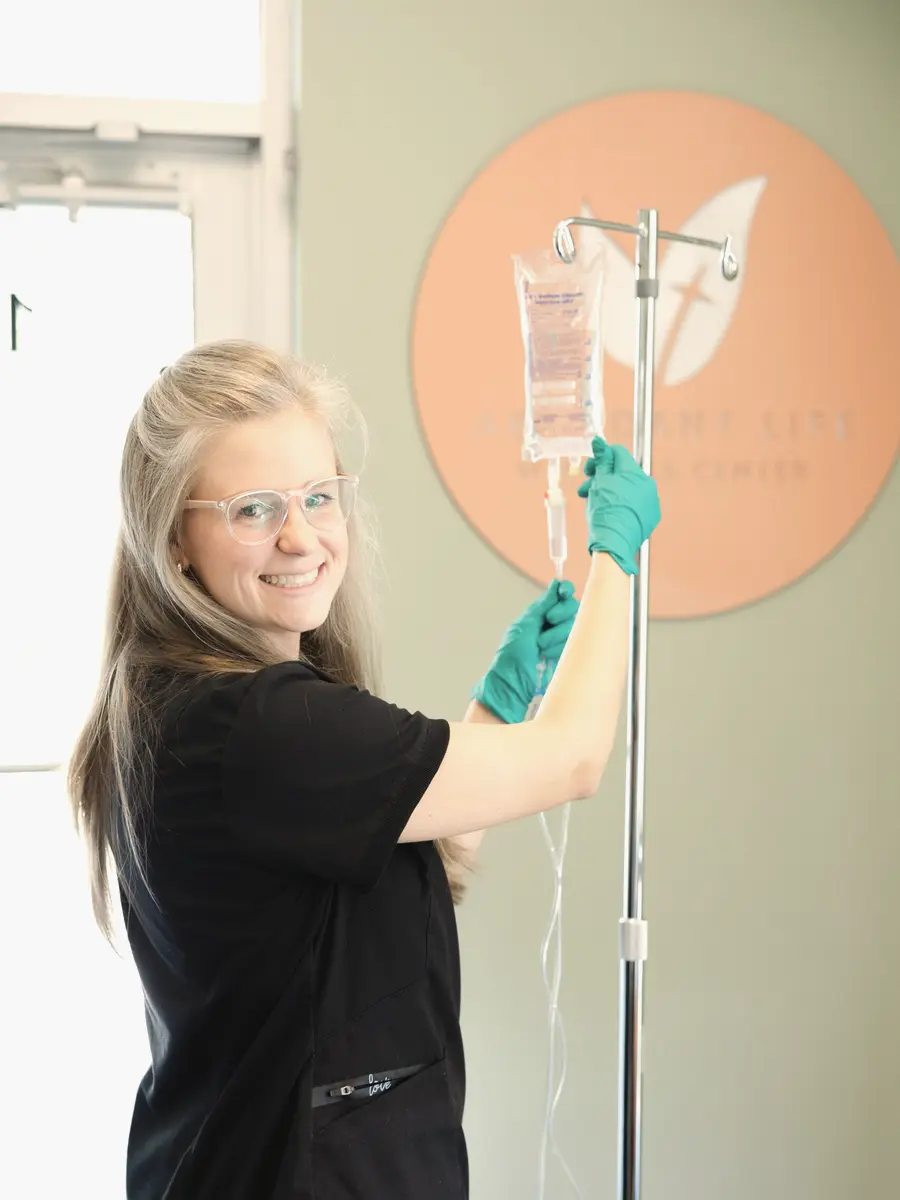 A practitioner preparing an IV beside the Abundant Life leaf sign