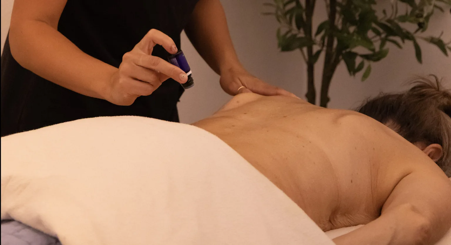 Therapeutic grade essential oils being dripped along a client&rsquo;s spine during a Raindrop Therapy session